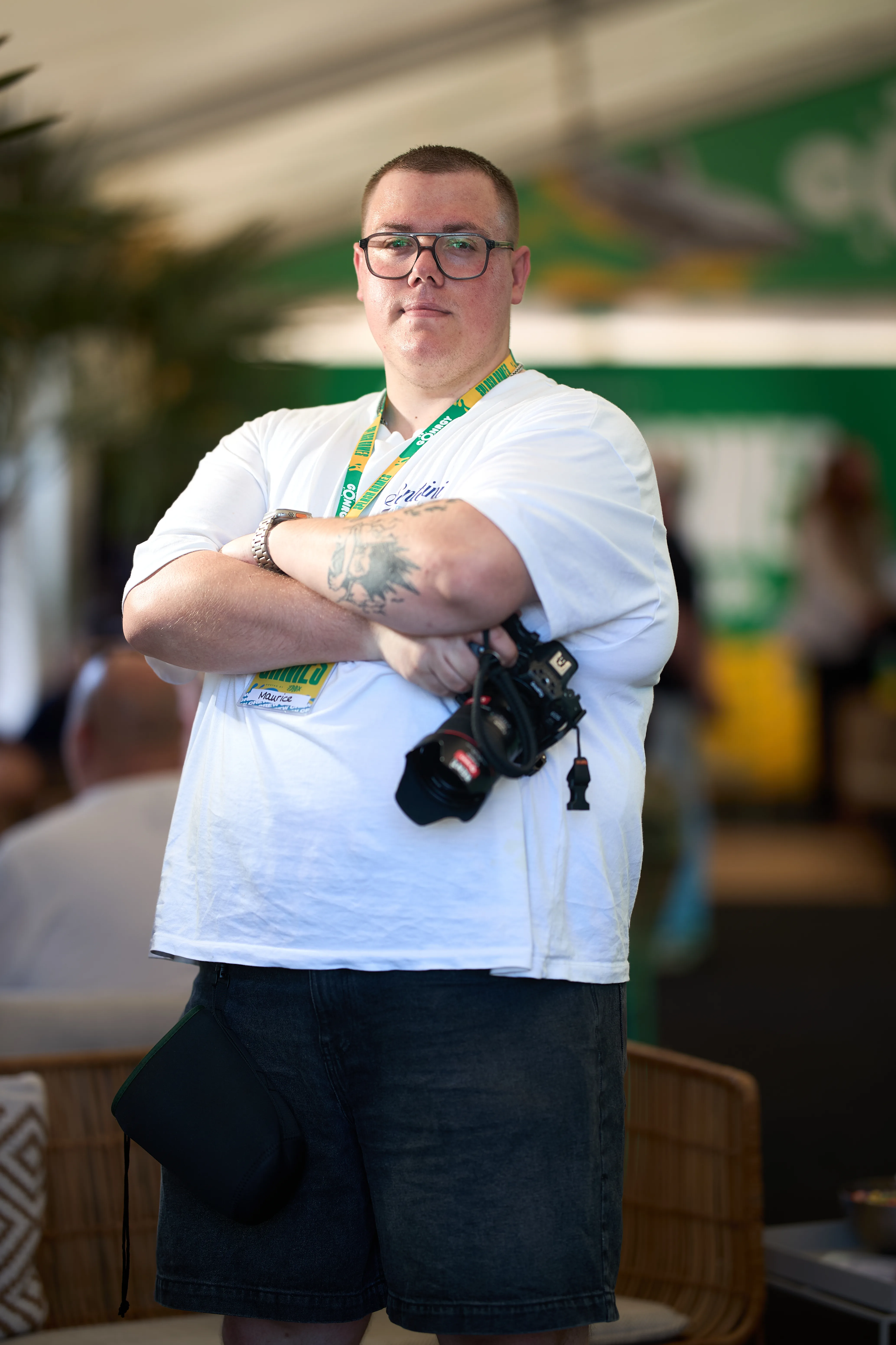 Maurice Krause – Fotograf mit verschränkten Armen und Kamera über der Schulter